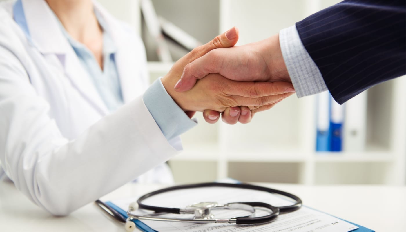 Doctor shaking hand with businessman in the office; pharma market insights concept