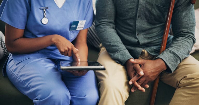 Closeup of a healthcare employee or caregiver with a senior patient on technology for health tips.